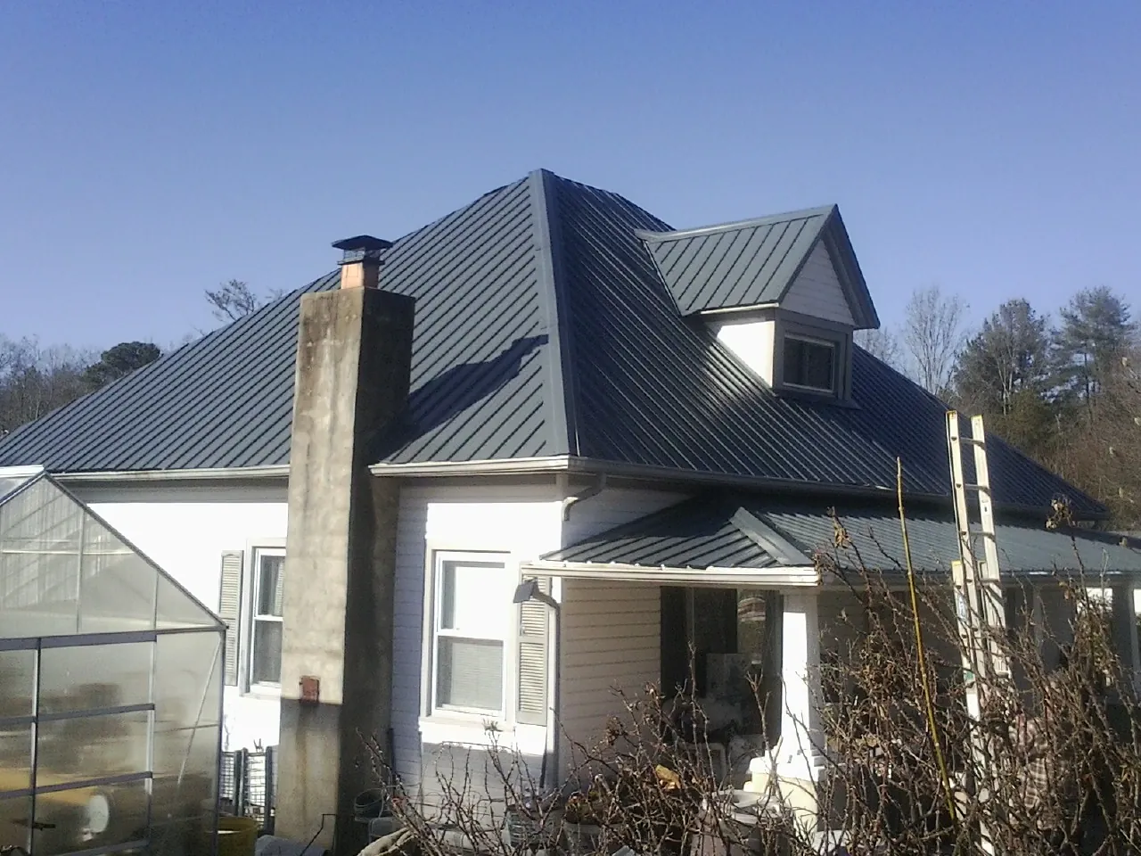Dark blue standing seam metal roof on a white farmhouse with dormer — Slate & Tile Roof Repair by Roofing Brothers in East Andover