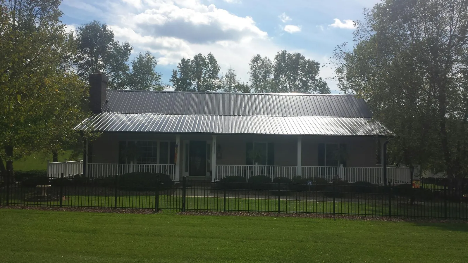 Gray metal roof on a brick ranch with a full width front porch — Gutter Guard Installation work by our crew in East Andover