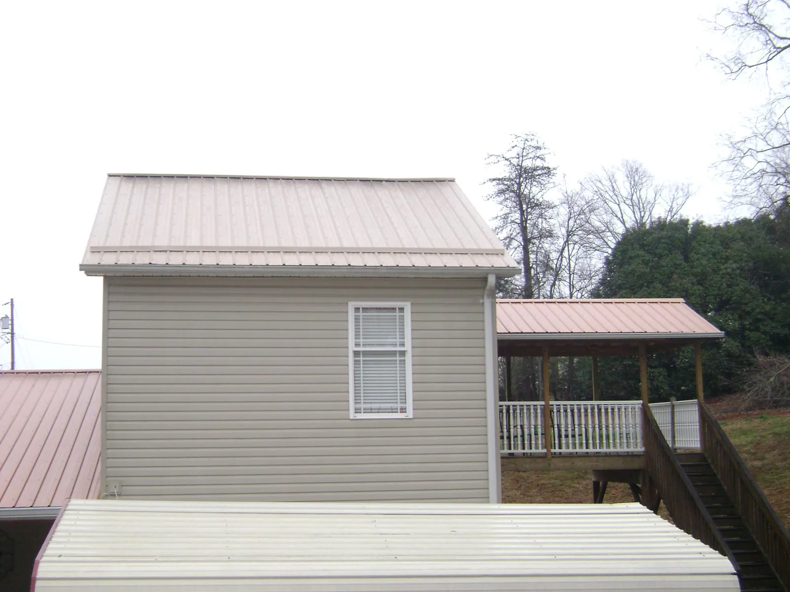Tan metal roofs on a two story addition and attached porch, from a Roof Replacement job in East Andover