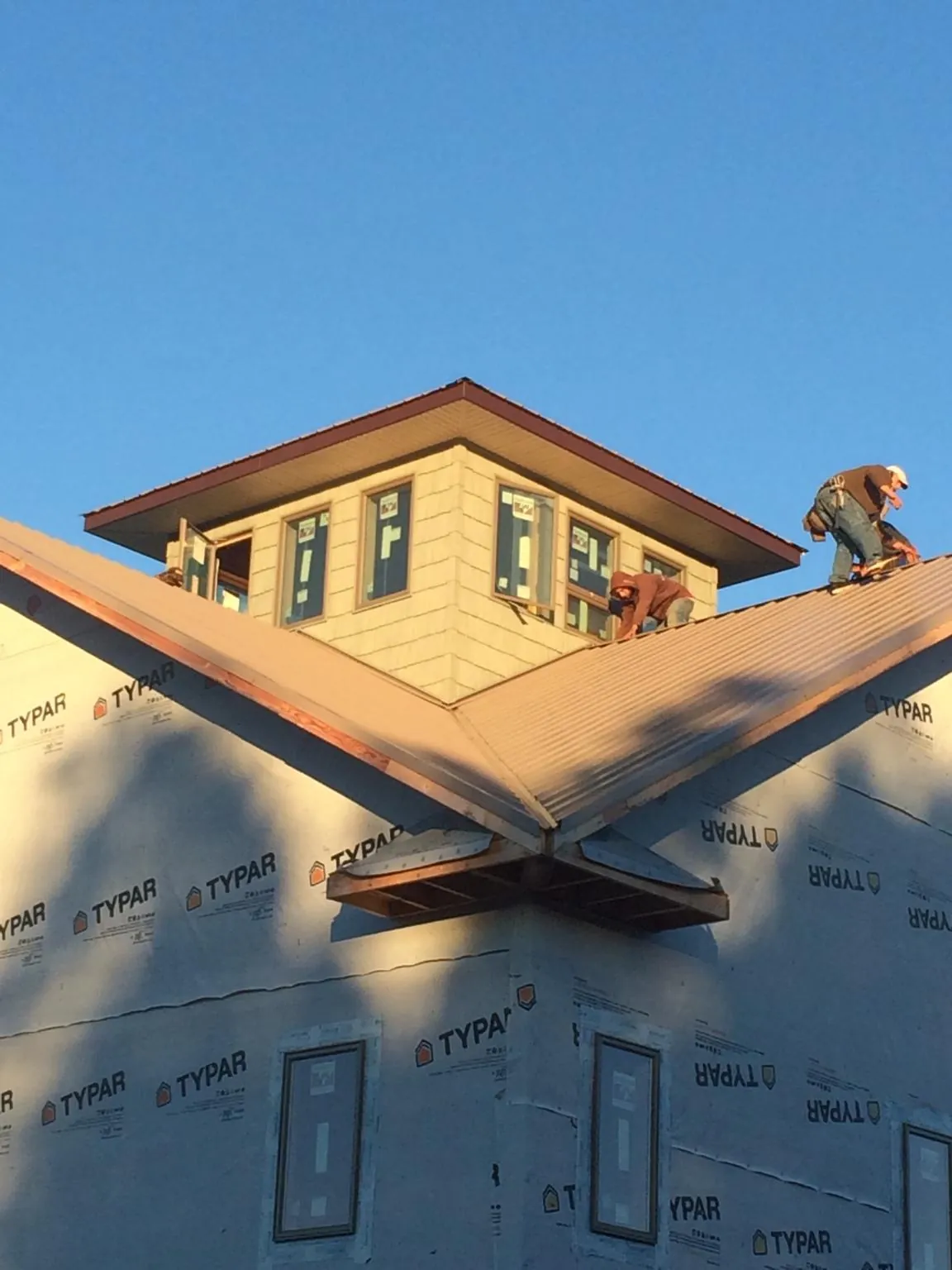 Roofers working around a rooftop cupola on a new metal roof at sunset — Roof Waterproofing in East Andover by Roofing Brothers